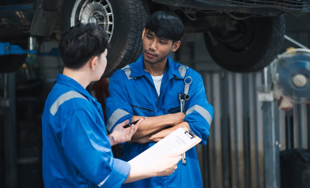 Asian mechanic repairing a car in auto repair shop.